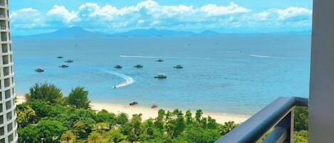 A view of a beach with boats, a clear sky, and a distant mountain range.