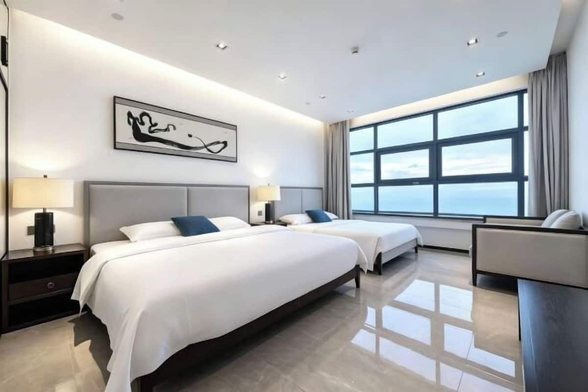 A modern hotel room with two beds, a large window, and a minimalist design.