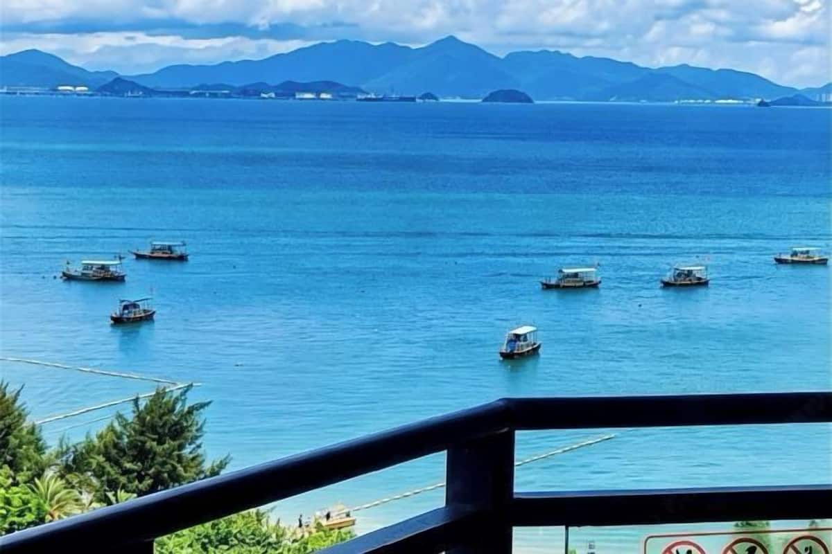 A coastal view with boats on the water and mountains in the distance.