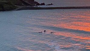 Atardecer costero con acantilados rocosos y mar tranquilo.