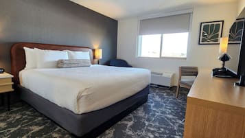 A hotel room with a large bed, two bedside tables, a desk, and a window.