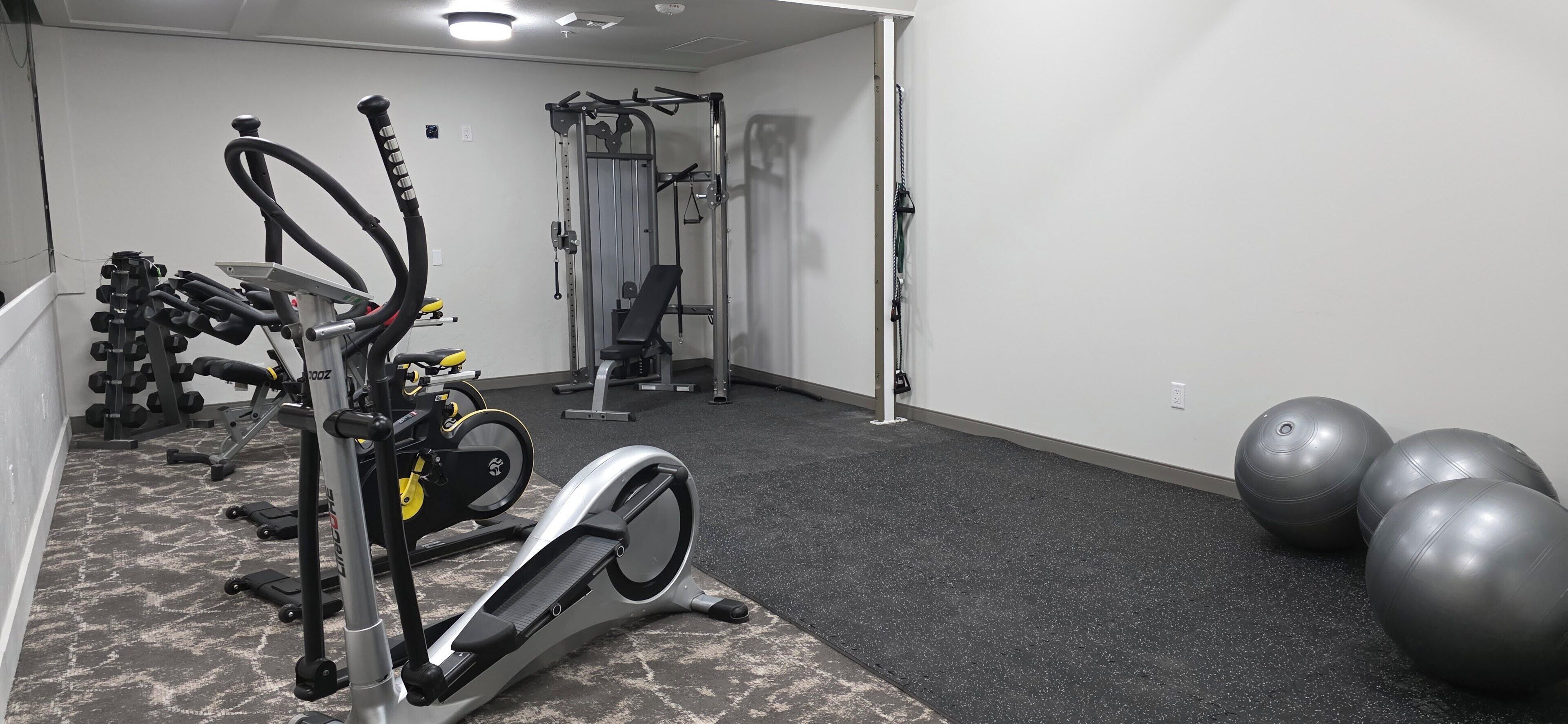 A gym with cardio equipment, weight machines, and exercise balls.
