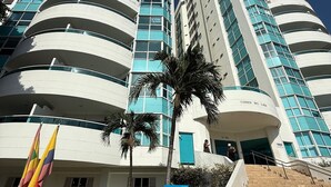 Un hotel moderno con fachada curva, varios balcones y una escalera que lleva a la entrada.