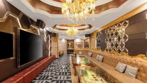 A luxurious living room with a large flat-screen TV, a patterned floor, a sofa, and a chandelier. - Meijingwan Hostel (Shenzhen)