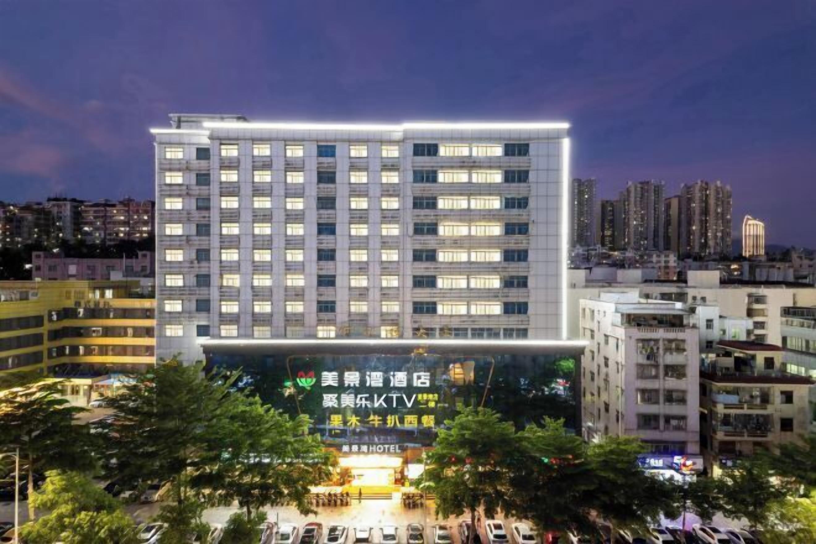 Um hotel com vários andares, um letreiro chamativo, estacionamento e edifícios ao redor.