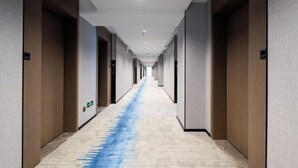 A long, narrow hotel corridor with wooden doors on both sides and a blue carpet running down the center. - Meijingwan Hostel (Shenzhen)