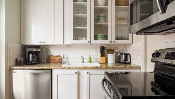 Een moderne keuken met witte kasten, een RVS vaatwasser, een zwart fornuis en een magnetron boven de aanrecht.