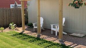 Een houten terras met Adirondack-stoelen en een hangende bloempot.