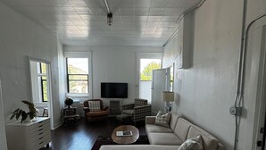 A spacious living room with a large sofa, a television, and a small table. - Charming 2-bedroom apartment in marvelous Chewelah with AC, WiFi (Chewelah)