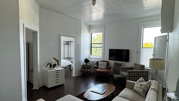 A spacious living room with a large sofa, a coffee table, and a television. There is a window providing natural light and a door leading to another room. - Charming 2-bedroom apartment in marvelous Chewelah with AC, WiFi (Chewelah)