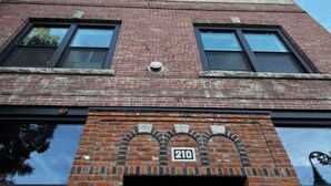 A red brick building with two windows and a door, featuring a number '210' on the facade. - Charming 2-bedroom apartment in marvelous Chewelah with AC, WiFi (Chewelah)
