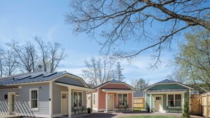A row of three single-story houses with attached garages, a gravel driveway, and a well-maintained lawn.