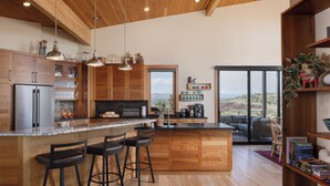 Cuina moderna amb armaris de fusta, una illa gran amb tamborets i vista a l'exterior.
