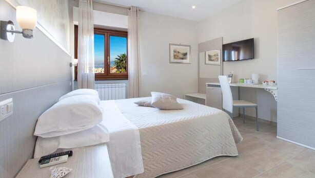 Une chambre d’hôtel moderne avec un grand lit, un bureau et une télévision.