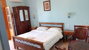 Een slaapkamer met een houten bed, een kledingkast, een nachtkastje, een stoel en een klein tafeltje.