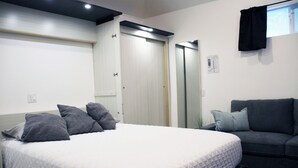 Une chambre à coucher avec un lit, un canapé gris et une armoire.