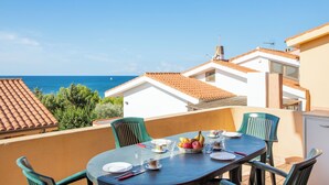 Un balcon avec une table préparée pour le petit-déjeuner, donnant sur la mer.