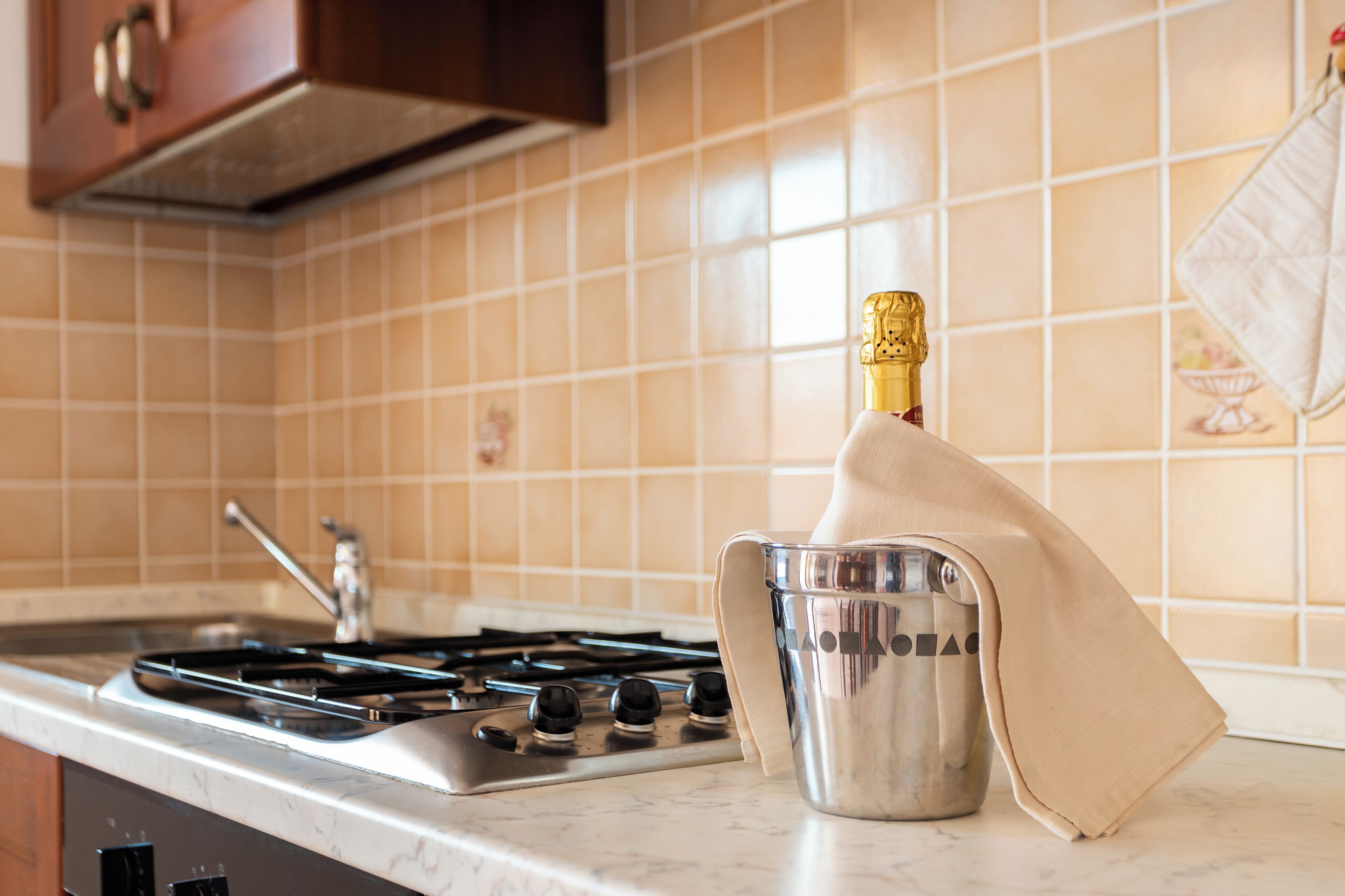 A kitchen with a gas stove, a stainless steel pot, and a towel draped over the pot.