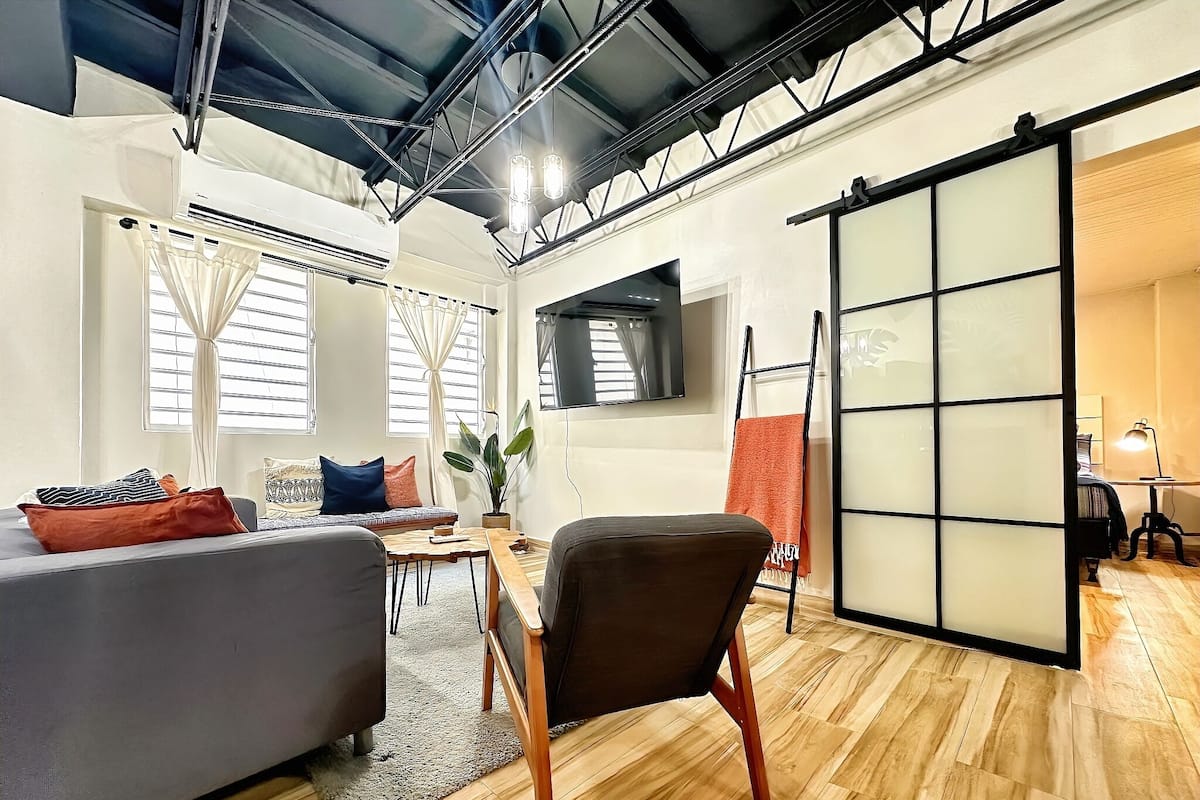 A modern living room with a sofa, a chair, a TV, and a sliding door.