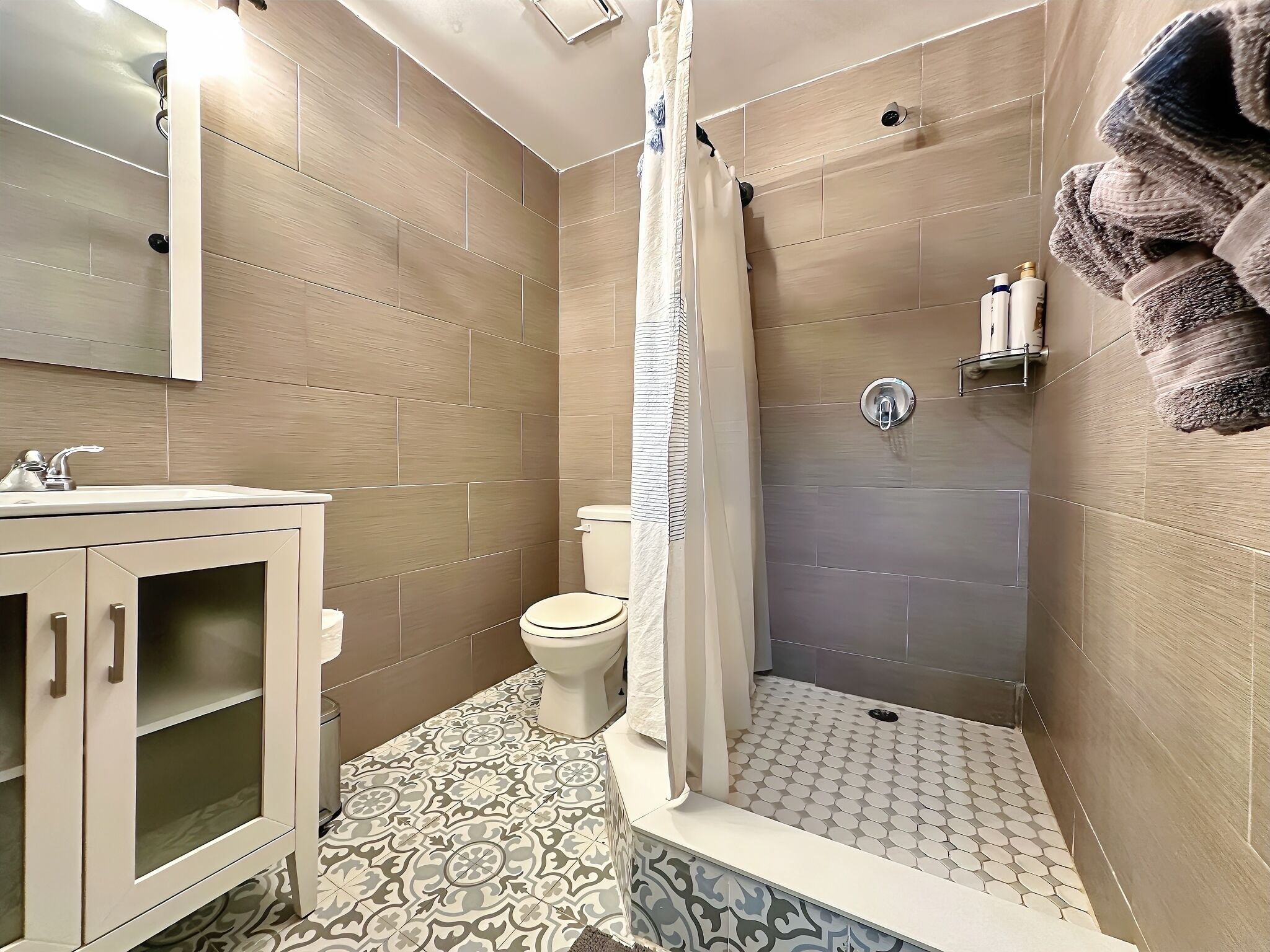 A bathroom with a shower, toilet, and sink.