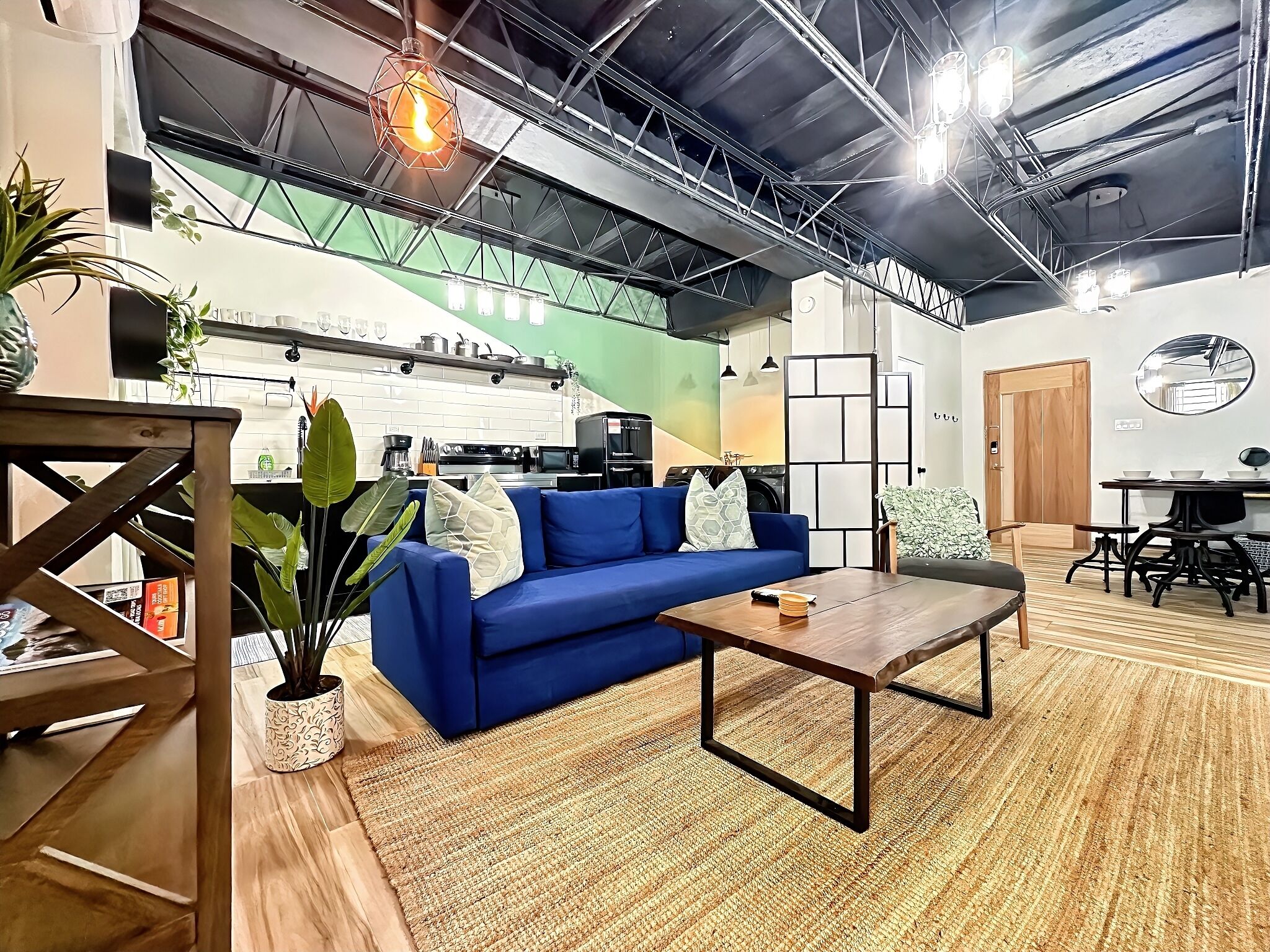 Un espacio habitable moderno con un sofá azul, una mesa de centro de madera y una cocina al fondo.