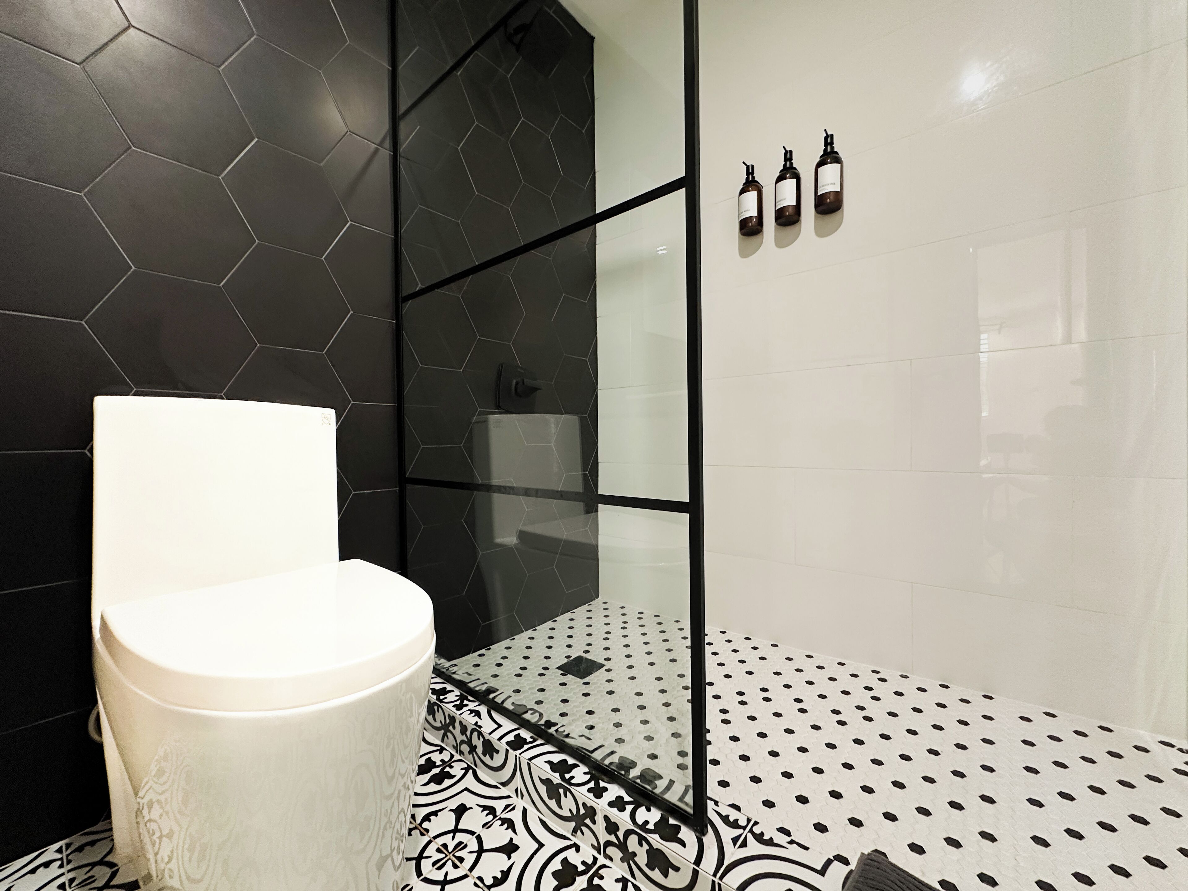 Une salle de bain avec des toilettes, une douche à parois de verre et des carreaux décorés.