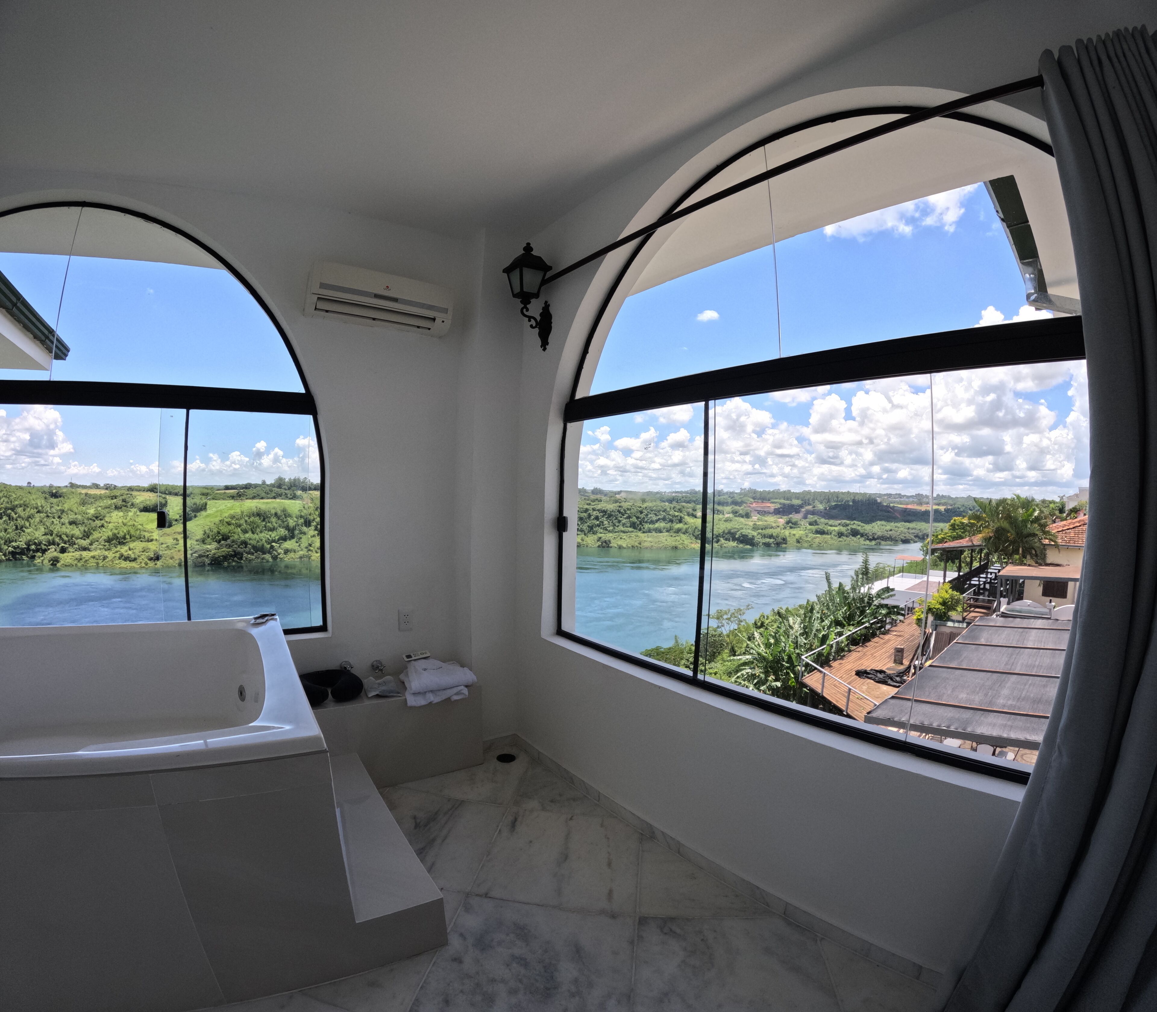 A bathroom with a bathtub and large windows offering a view of a river and greenery.