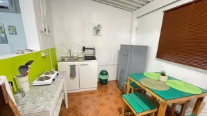 Una cocina compacta con fregadero, encimera y un pequeño comedor con mesa y sillas.
