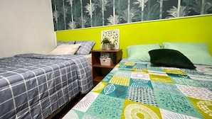 Una habitación con dos camas individuales, cada una con una colcha de estampado diferente. Hay una mesita de noche con un pequeño adorno entre las camas.