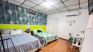 Habitació amb dos llits, una taula de treball i aire condicionat.