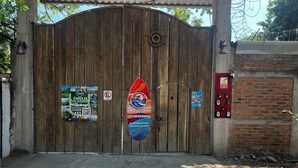 Una puerta de madera con un letrero que dice 'Rancho Los Hermanas' y un cartel de 'prohibido acampar'.