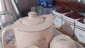 Una kitchenette con cafetera, recipientes para té y azúcar, y botellas de agua.