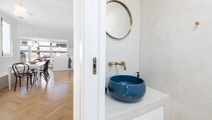 A modern kitchen with a white countertop, a blue sink, and a brass faucet.