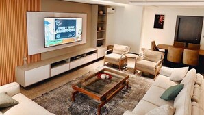 Un salon moderne doté d’un téléviseur à écran plat, de sièges confortables et d’étagères intégrées.