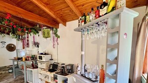 A kitchen with a wooden ceiling, a refrigerator, a sink, a microwave, and a shelf with bottles and glasses. - Mama Eva House (Lago Puelo)