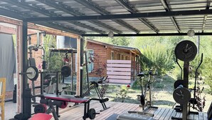 An outdoor gym with various exercise equipment, including a bench, kettlebells, and weight machines. - Mama Eva House (Lago Puelo)