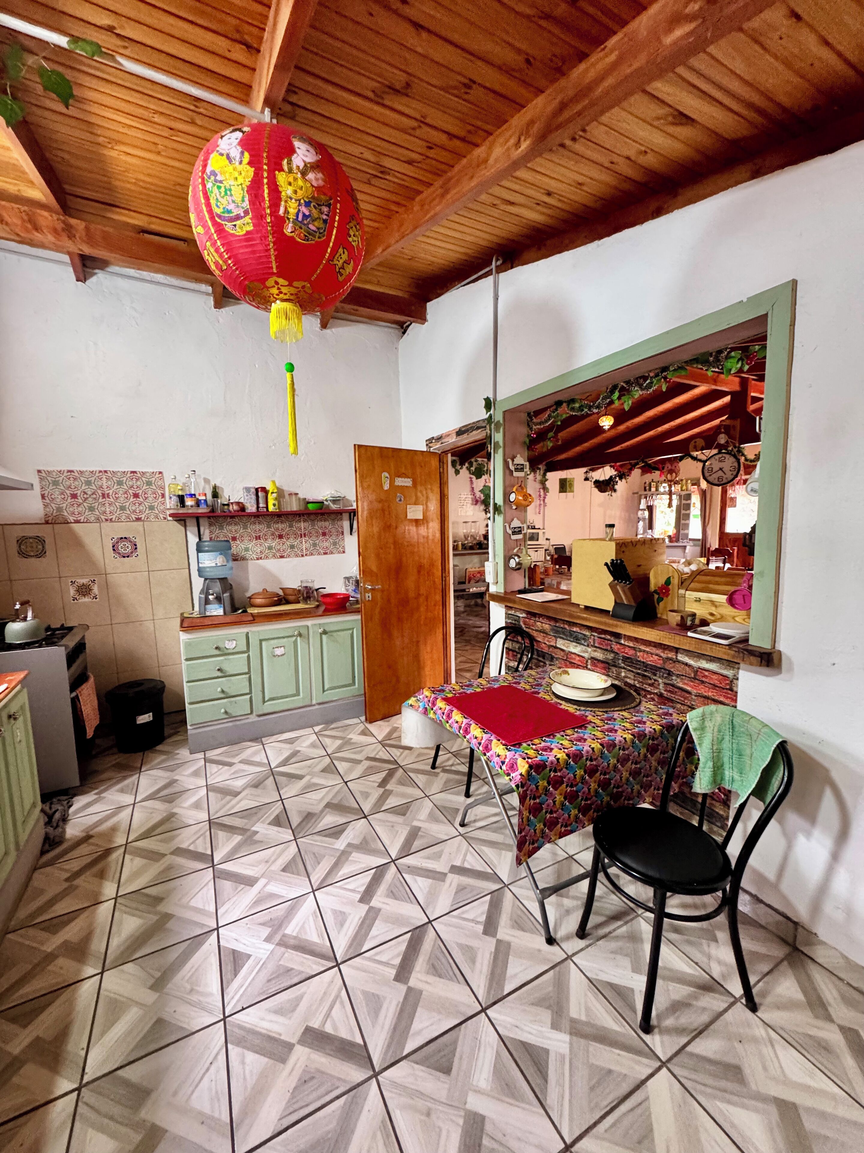 A kitchen with a dining table, chairs, and a hanging lantern.
