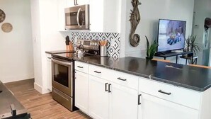 A modern kitchen with white cabinets, a stainless steel oven, a microwave, and a black countertop.