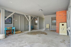 A room with a concrete floor, a door leading to another room, a blue chair, a white chair, and a wall-mounted sign. - 5BR 4BA OF Beach House. LOTS of Charm (North Myrtle Beach)