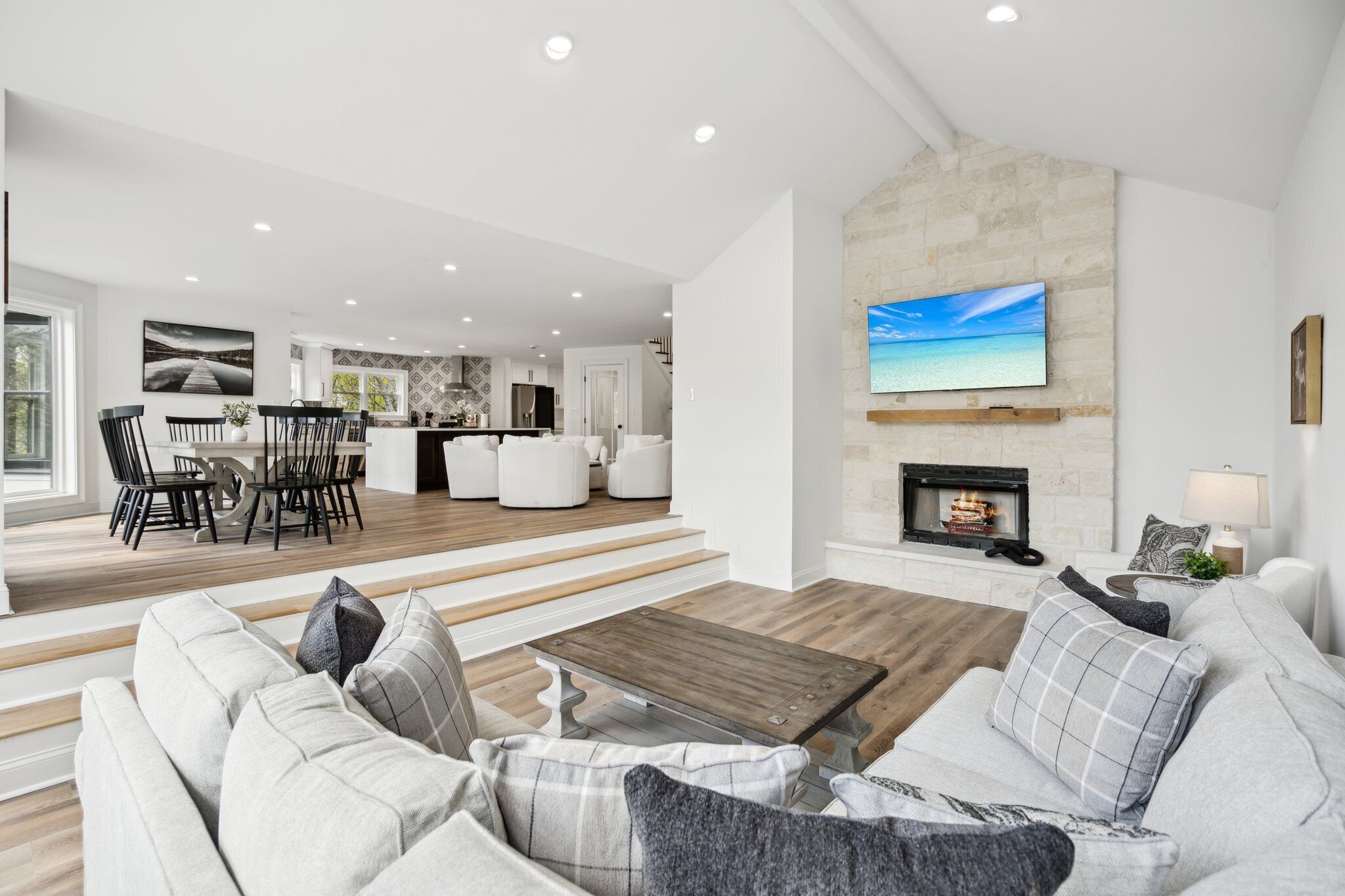 Amplia sala de estar con chimenea, comedor y televisor grande montado en la pared.