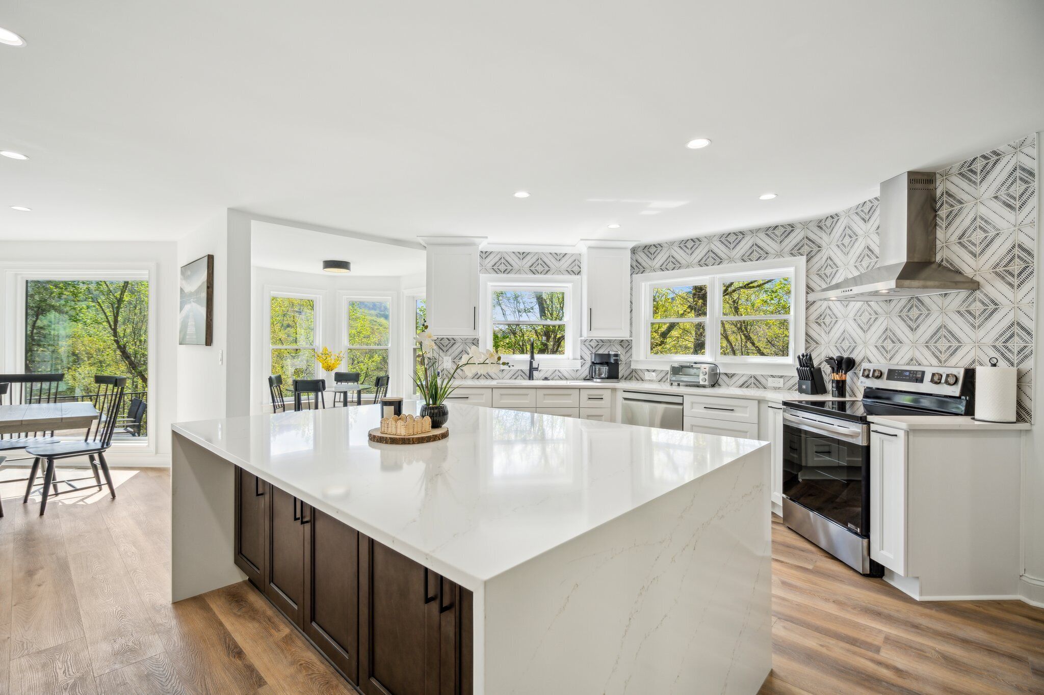 A modern kitchen with a large island, white cabinetry, and a patterned backsplash.