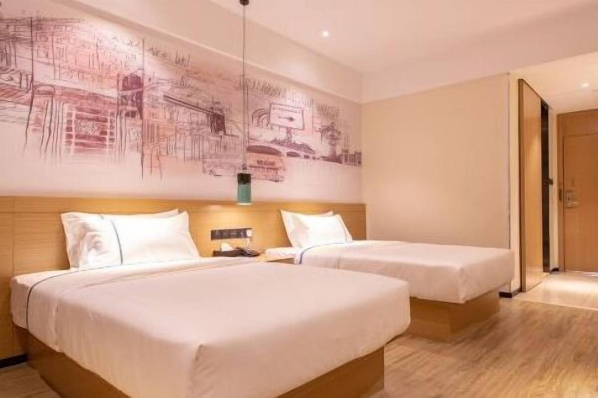 Una habitación de hotel con dos camas, un mural grande en la pared y piso de madera.