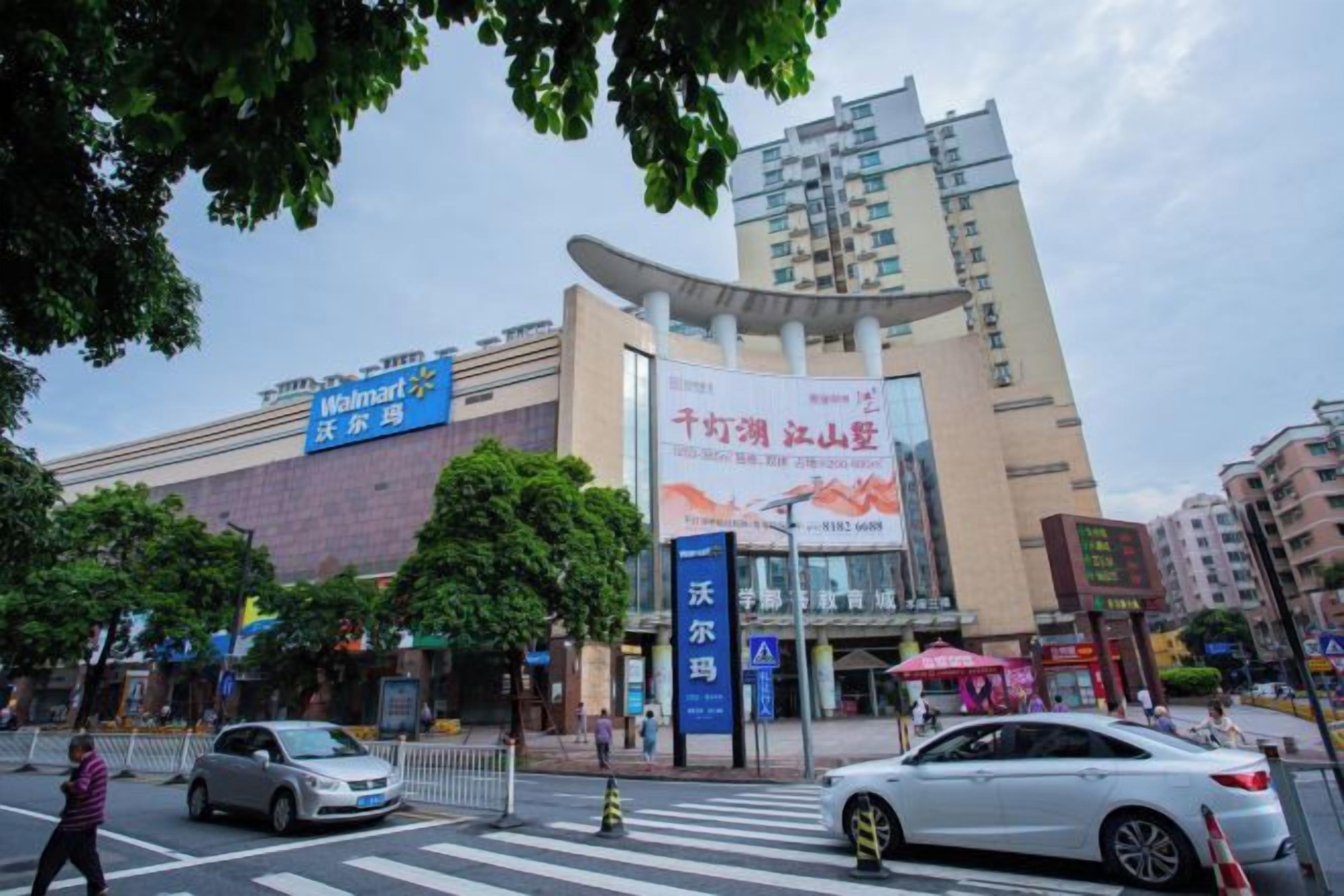 A multi-story building with a large sign, a pedestrian crossing, and vehicles on the road.