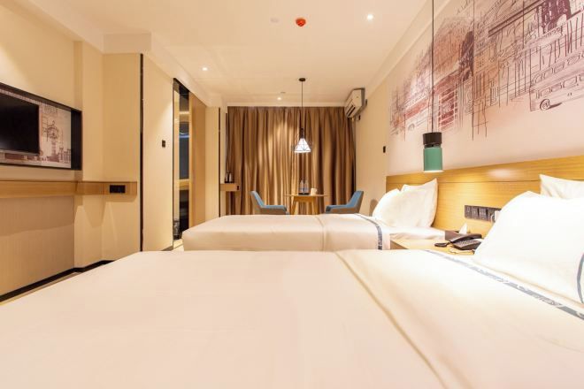 A hotel room with two beds, a TV, a desk, and a chair.