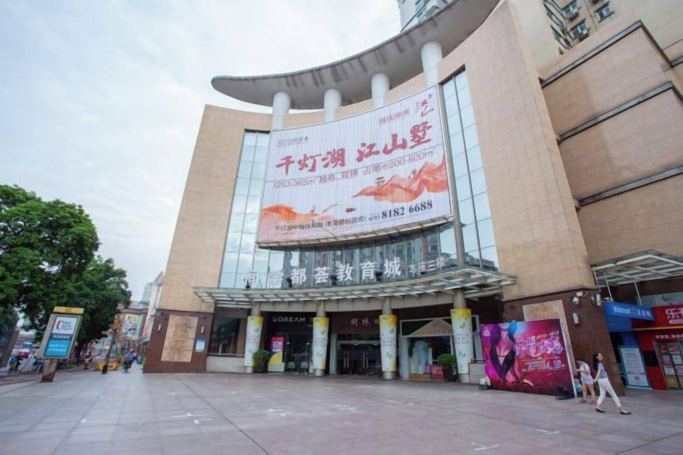 A large building with a curved facade, multiple columns, and a prominent advertisement.