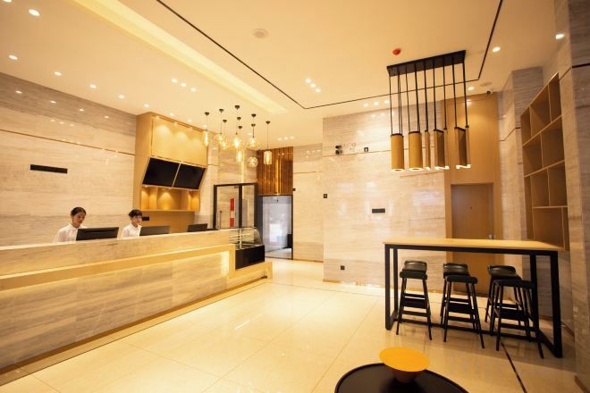 Un hall d’hôtel moderne comprenant un comptoir d’accueil, un bar et un espace détente avec des sièges.