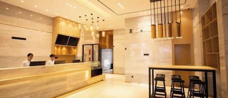 A modern hotel lobby with a reception desk, bar area, and seating.