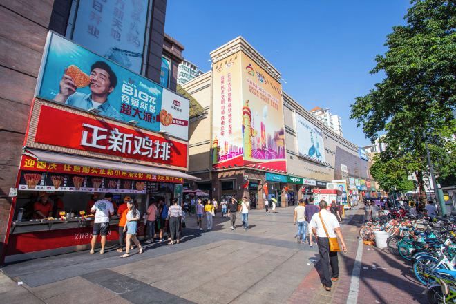 A busy urban street with various storefronts and pedestrians.