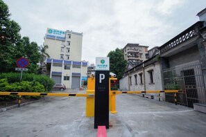 A gated parking area with a yellow barrier, a 'P' sign, and a building with a blue and white facade in the background. - Guiyuan Hotel (Foshan Lingnan Tiandi Oriental Plaza Branch) (Foshan)