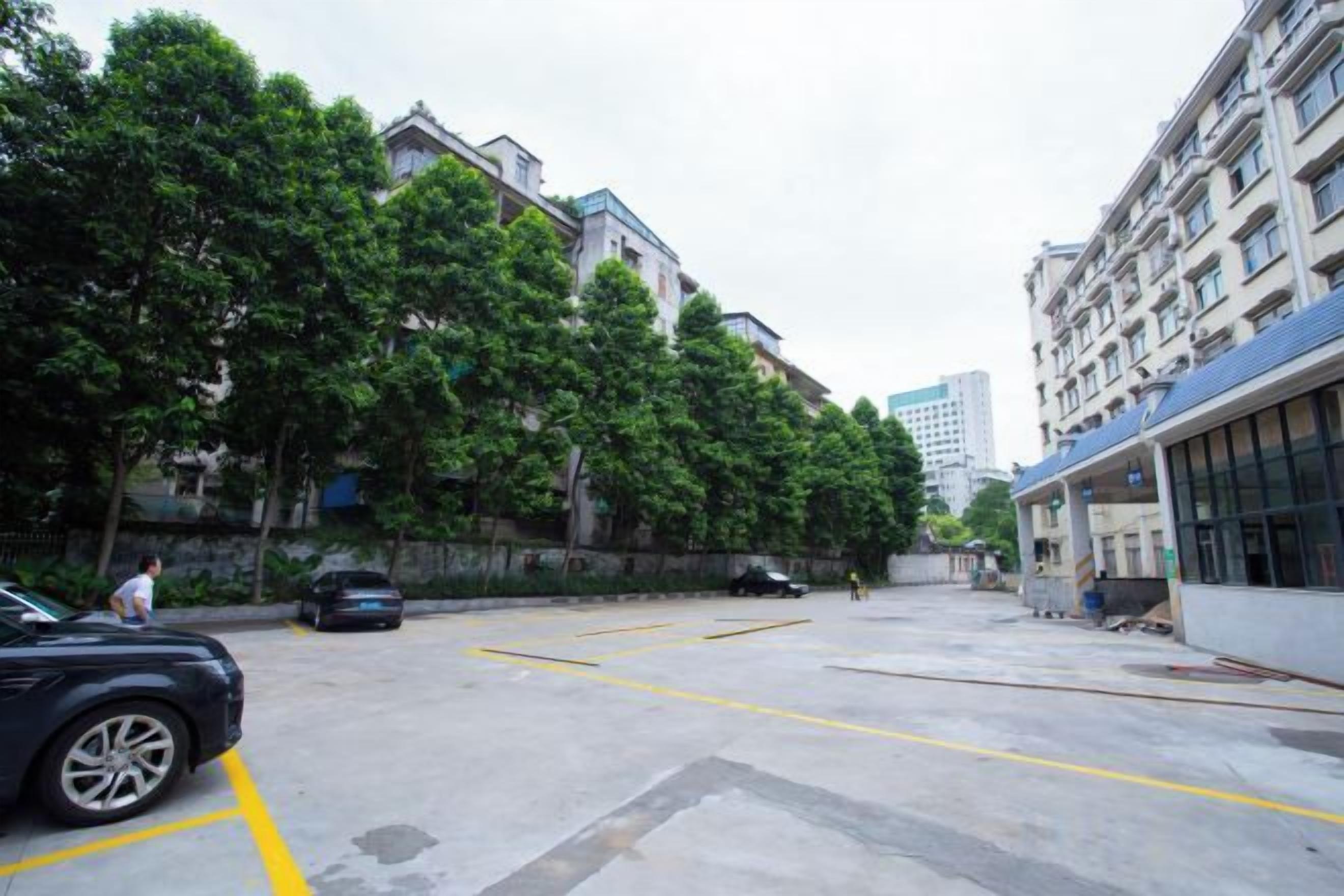 A parking lot with cars, a building with a blue roof, and trees.